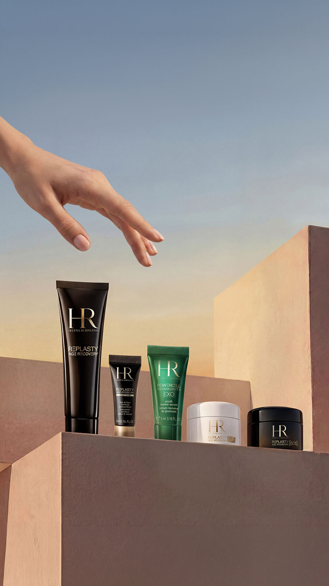 An elegant hand hovers over a selection of Replasty and Powercell skincare products arranged on geometric podiums in nude and powdery tones, against a clear sky background at twilight.