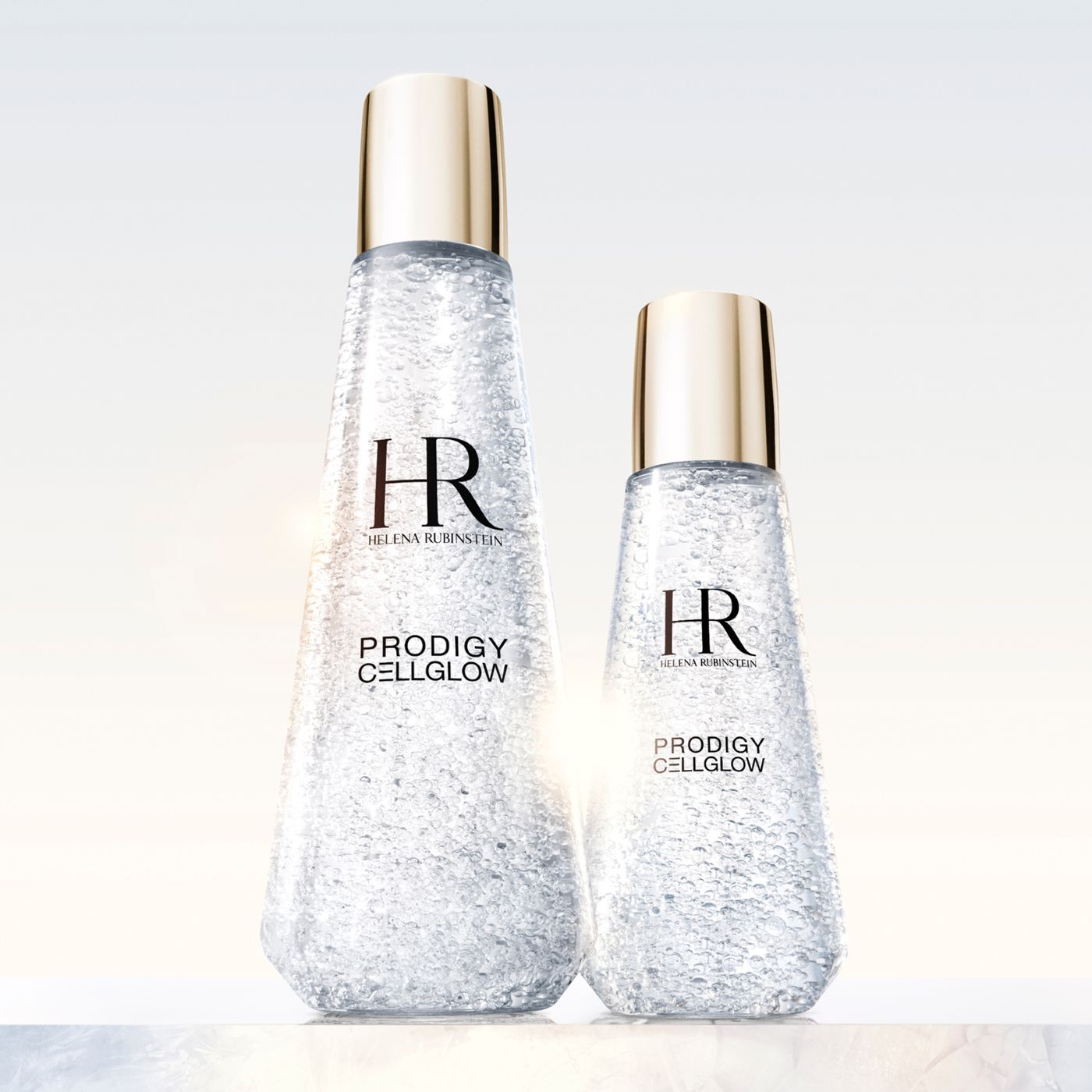 Helena Rubinstein Prodigy Cellglow: the essence of regenerated skin. Two crystal-pure bottles, their fine bubbles reflecting light, promise a rebirth of radiance and vitality. The art of light on skin.
