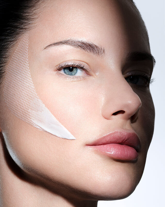 Womans face with Helena Rubinstein REPLASTY cream and innovative bandage texture on her cheek.