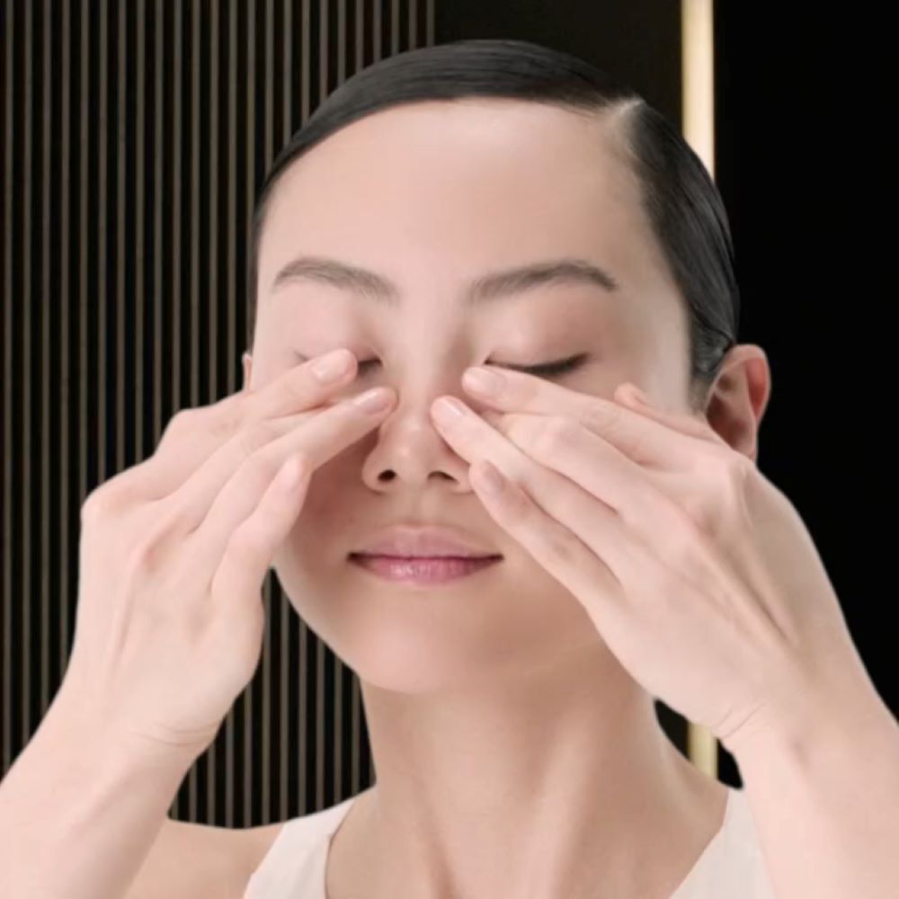Woman massaging eye contour, fingers on eyelids.