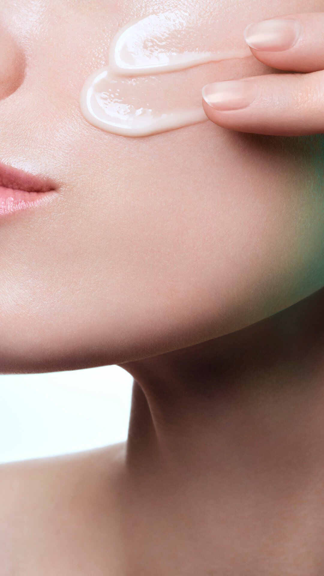 Woman's face with a white cream streak on her cheek.