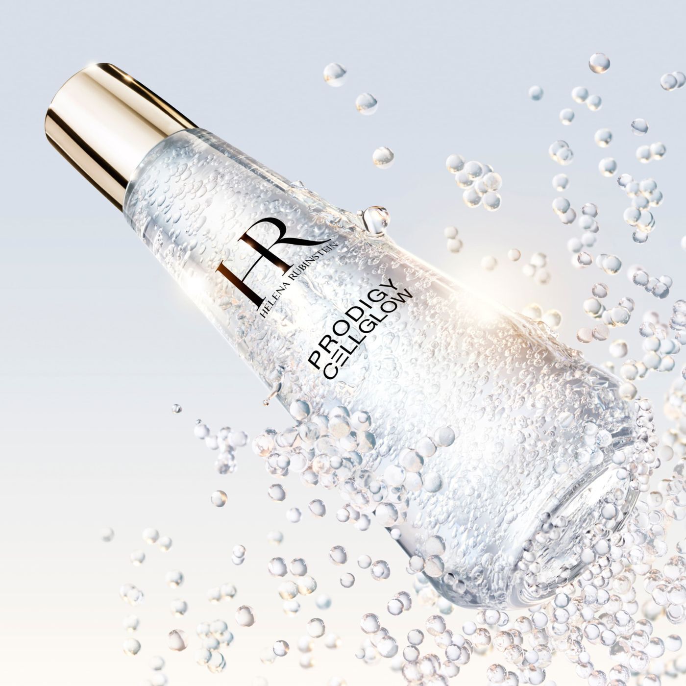 "Helena Rubinstein Prodigy Cellglow" serum bottle filled with bubbles, tilted and surrounded by sparkling suspended bubbles, on a bright and luminous background.